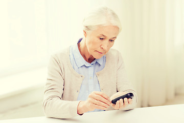 Image showing senior woman with glucometer checking blood sugar