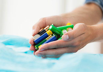 Image showing close up of hands putting batteries to rubbish bag