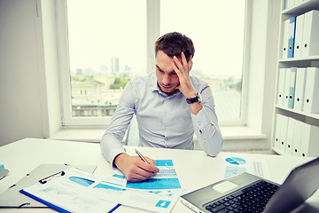 Image showing stressed businessman with papers in office