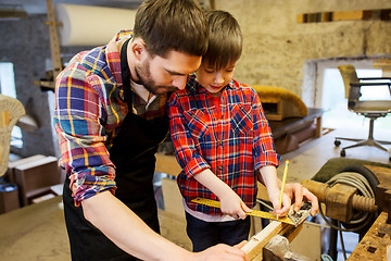 Image showing father and son with ruler measure wood at workshop