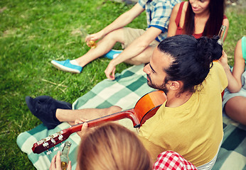 Image showing happy man with friends playing guitar at camping