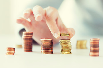 Image showing close up of female hand putting coins into columns