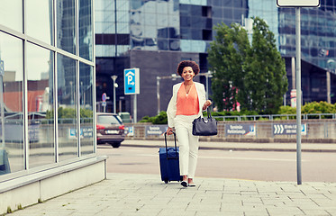 Image showing happy young african woman with travel bag in city