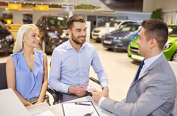 Image showing happy couple with car dealer in auto show or salon