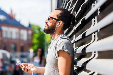 Image showing happy man with earphones and smartphone in city