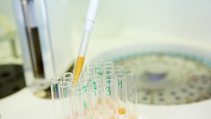 Image showing pipette dropping sample into a test tube,abstract science background