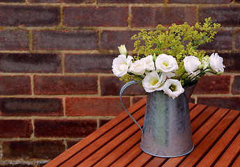 Image showing White prairie gentians in a jug on a wooden table