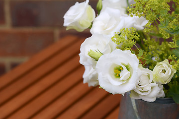 Image showing White tulip gentians with ladys mantle on a wooden table