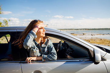 Image showing happy teenage girl or young woman in car