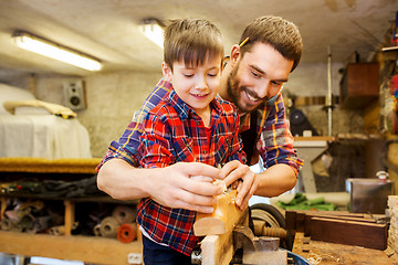 Image showing father and son with plane shaving wood at workshop