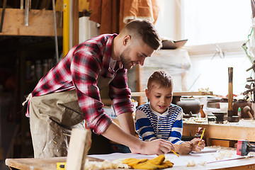 Image showing happy father and son with blueprint at workshop