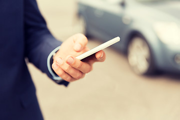 Image showing close up of man hand with smartphone and car