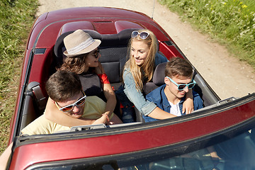 Image showing happy friends driving in cabriolet car at country