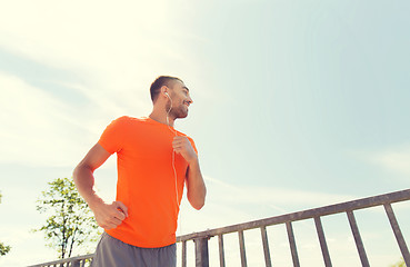 Image showing happy man with earphones running outdoors