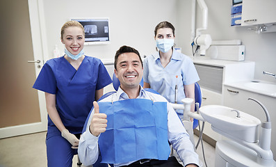 Image showing happy female dentists with man patient at clinic