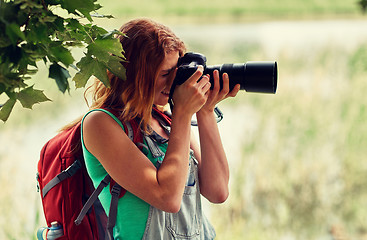 Image showing young woman with backpack and camera outdoors