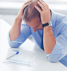 Image showing stressed businessman with papers at work