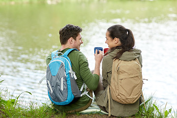 Image showing happy couple with cups drinking in nature