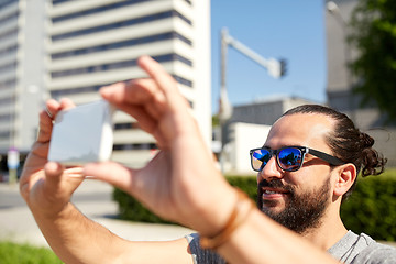 Image showing man taking video or selfie by smartphone in city