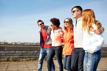 Image showing happy teenage friends walking along city street