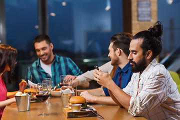 Image showing man with smartphone and friends at restaurant