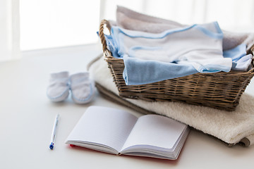 Image showing close up of baby clothes for newborn and notebook