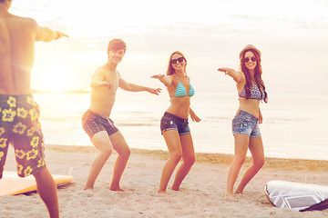 Image showing smiling friends in sunglasses with surfs on beach