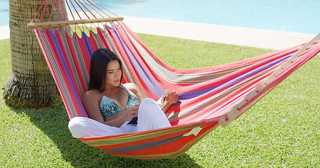 Image showing Single woman in bikini reading a book in hammock