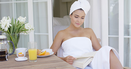 Image showing Woman in bath towel reading book at table