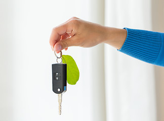 Image showing close up of hand holding car key with green leaf