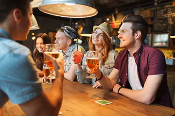 Image showing happy friends with drinks talking at bar or pub