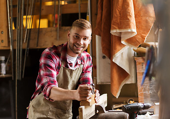 Image showing carpenter working with plane and wood at workshop