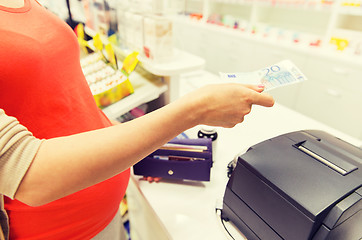 Image showing pregnant woman with money at cashbox in drugstore