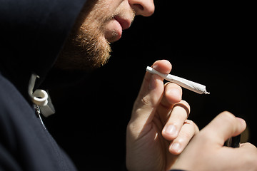 Image showing close up of addict lighting up marijuana joint