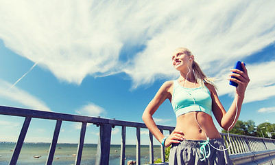 Image showing happy woman with smartphone and earphones outdoors