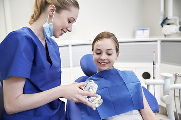 Image showing happy dentist showing jaw model to patient girl