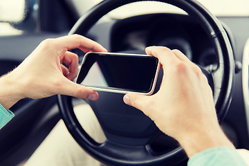 Image showing close up of man hand with smartphone driving car