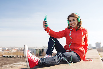 Image showing happy young woman with smartphone and headphones