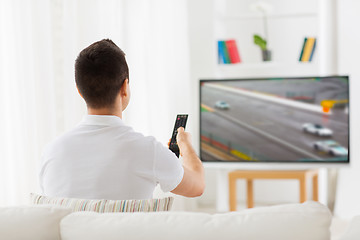 Image showing man with remote watching motorsports on tv at home