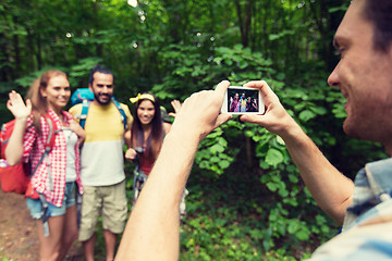 Image showing happy man photographing friends by smartphone