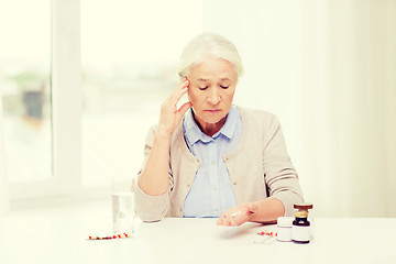 Image showing senior woman with water and medicine at home