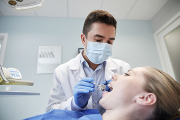 Image showing male dentist in mask checking female patient teeth