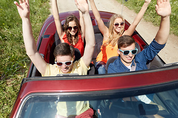 Image showing happy friends driving in cabriolet car at country