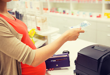 Image showing pregnant woman with money at cashbox in drugstore