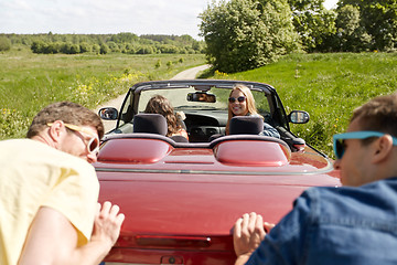 Image showing happy friends pushing broken cabriolet car