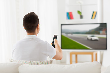 Image showing man with remote watching motorsports on tv at home