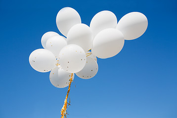 Image showing close up of white helium balloons in blue sky