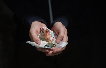 Image showing close up of addict hands with drugs and money