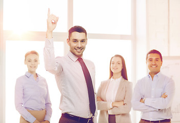 Image showing smiling businessman in office with team on back