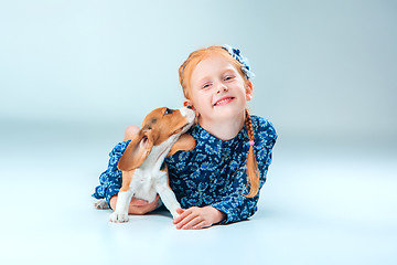 Image showing The happy girl and a beagle puppie on gray background